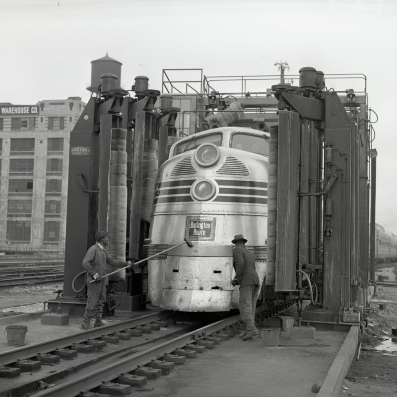 Zephyr train A large metal train being cleaned by two workers from the CB&Q railroad company