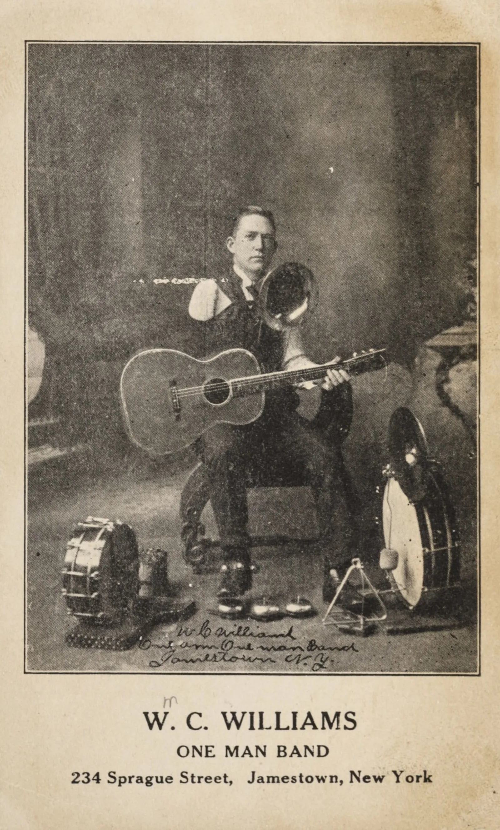 Mendicant literature 007 o3 WC Williams photo 2 Williams seated with his many instruments, including a guitar, trombone, and multiple drums.