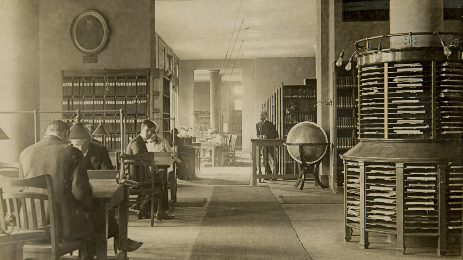 Historic Newberry reading room An old photo from around 1900 shows several people studying at desks. One person looks over his right shoulder at the photographer.