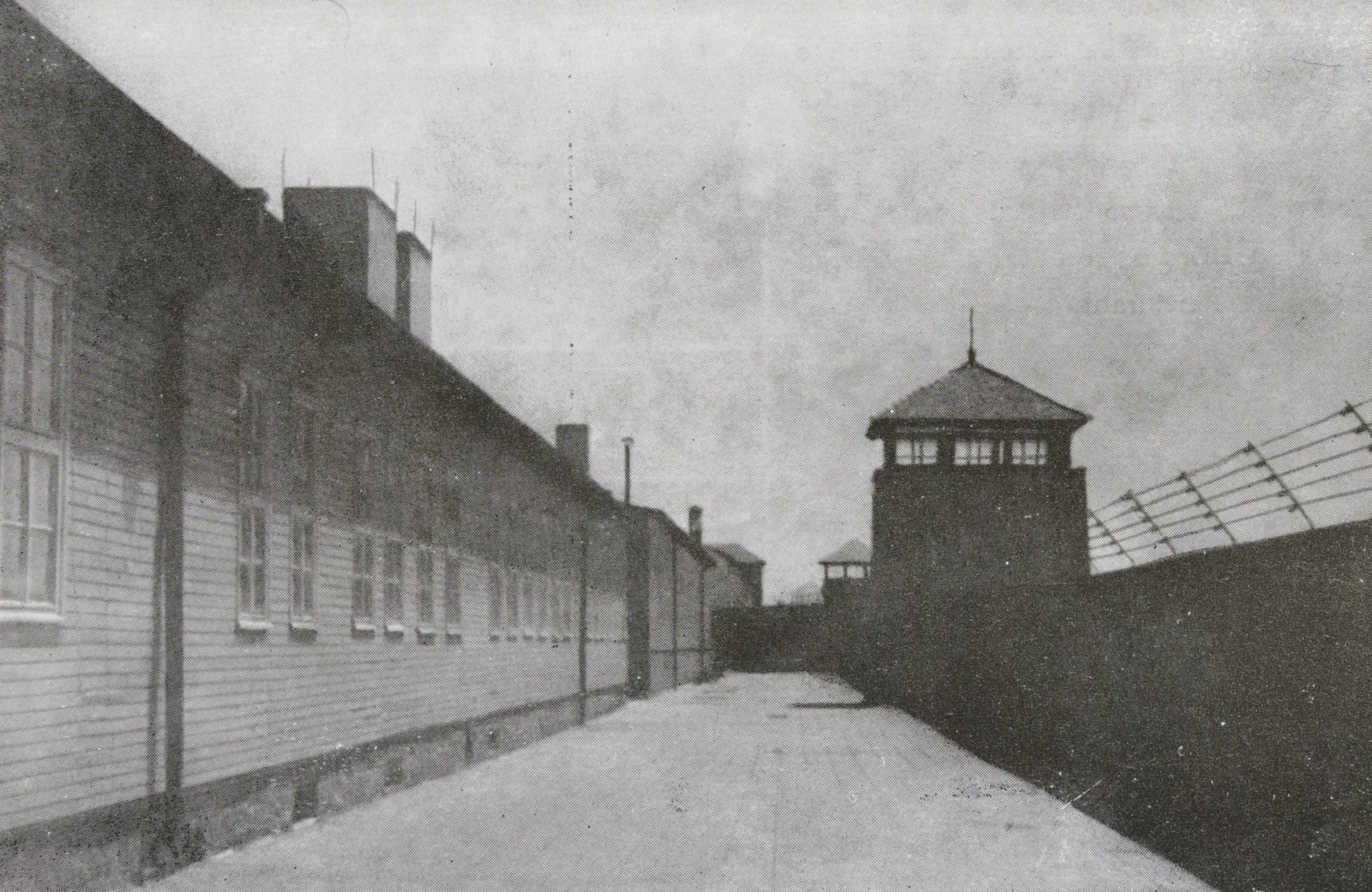 View of the concentration camp View of the concentration camp: a wall with barbed wire and a watchtower.
