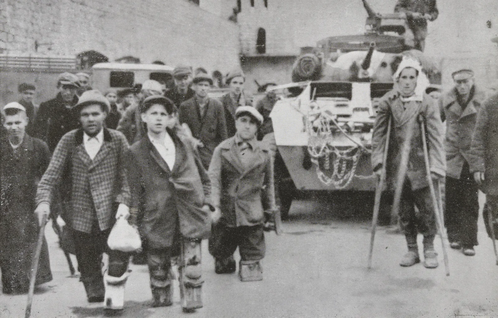 Prisoners with disabilities Photo of prisoners. Some are walking with crutches. Behind them is a tank.